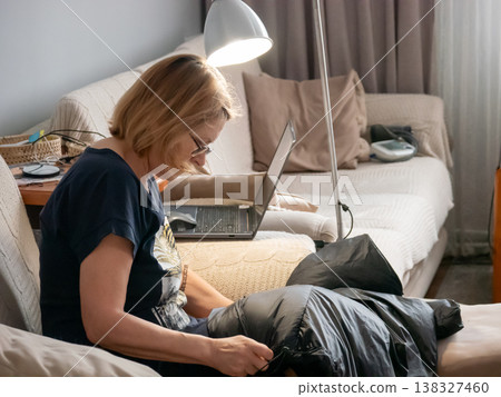 Woman sitting on sofa and packing black bag in living room. Freelancer working with laptop at home. Cozy interior, remote job and telecommuting concept for modern busy lifestyle. Woman sitting on sofa and packing black bag in living room. Freelancer working with laptop at home. Cozy interior, remote job and telecommuting concept for modern busy lifestyle. 138327460