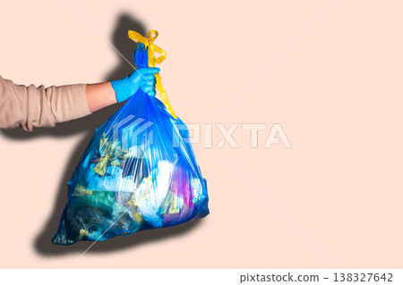 Hand holding full garbage bag on beige background isolated. High quality image Hand holding full garbage bag on beige background isolated. High quality image 138327642