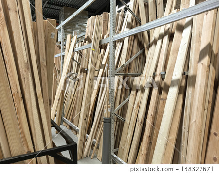 Wooden boards stacked high in a spacious lumber store during daylight hours 138327671