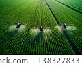 Three drones apply treatment to rows of green crops in a large farm field 138327833