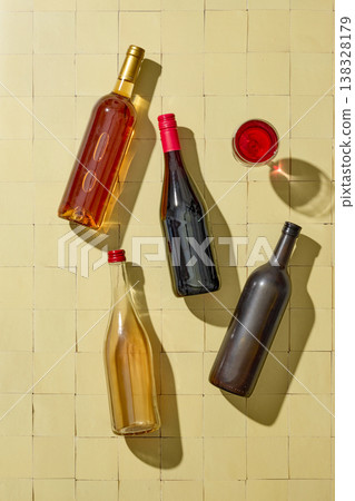 Assorted wine bottles and glasses on light yellow background, top view Assorted wine bottles and glasses on light yellow background, top view 138328179