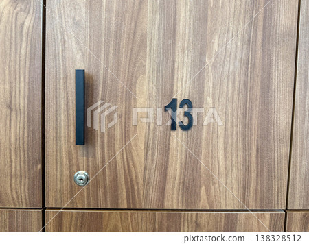 Close up of wooden locker door with number thirteen and metal handle in changing room. Personal storage identification, security access system and facility organization detail Close up of wooden locker door with number thirteen and metal handle in changing room. Personal storage identification, security access system and facility organization detail 138328512