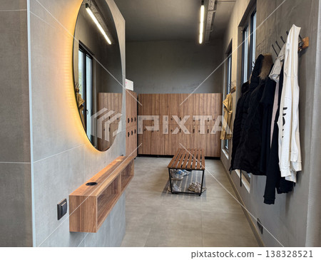 Modern locker room interior with wooden lockers bench mirror and hanging clothes in sports facility. Changing area usage, storage organization, fitness infrastructure and daily routine concept 138328521