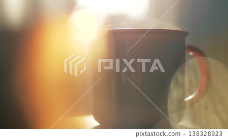 Steam rising from ceramic mug in warm morning sunlight Steam rising from ceramic mug in warm morning sunlight 138328923