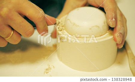Close up of potter refining the edge of a plaster slip casting mold with a knife in a ceramics workshop 138328948