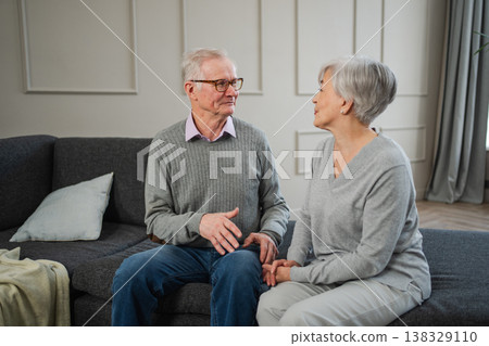 Senior adult mature couple talking at home. Mid age old husband and wife speaking smiling laughing enjoying time together. Grandmother grandfather spending time together. Family moment love and care Senior adult mature couple talking at home. Mid age old husband and wife speaking smiling laughing enjoying time together. Grandmother grandfather spending time together. Family moment love and care 138329110
