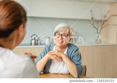 Female doctor examining older senior woman in doctor office or at home. Old woman lady patient and doctor have consultation in hospital room. Medicine healthcare medical checkup. Visit to doctor 138329155