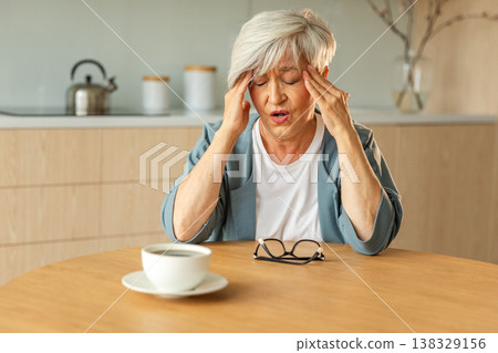 Headache pain. Unhappy middle aged senior woman suffering from headache sick rubbing temples at home. Mature old senior grandmother touching temples experiencing stress Woman feeling pain hurt in head 138329156