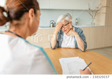 Female doctor examining older senior woman in doctor office or at home. Old woman lady patient and doctor have consultation in hospital room. Medicine healthcare medical checkup. Visit to doctor 138329157