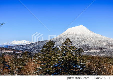Snow-covered Mt. Meakan and Mt. Oakan, a mountain landscape against a clear blue sky. 138329227