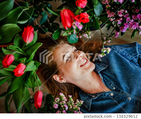Smiling woman lying among blooming spring flowers. Smiling woman lying among blooming spring flowers. 138329612