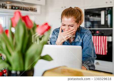 Mature woman searching recipe online on laptop while cooking in kitchen. Mature woman searching recipe online on laptop while cooking in kitchen. 138329618
