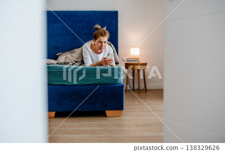 Middle aged woman using smartphone while lying in bed at home. 138329626
