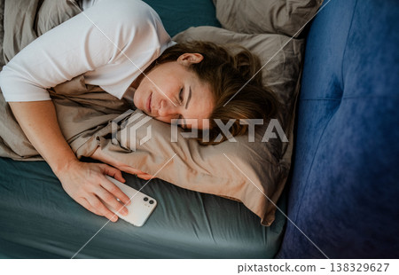 Mature woman sleeping with smartphone in hand. Mature woman sleeping with smartphone in hand. 138329627
