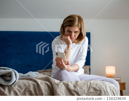 Mature woman reading concerning text on phone. Mature woman reading concerning text on phone. 138329630