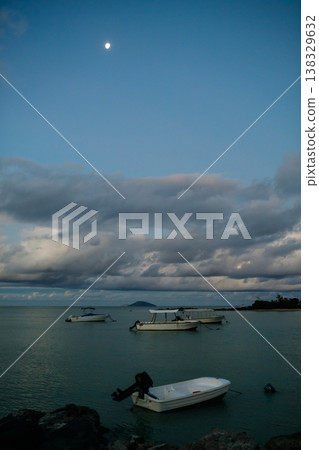 Boats on calm sea at night in Mauritius tropical resort with golden light. Boats on calm sea at night in Mauritius tropical resort with golden light. 138329632