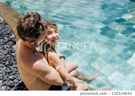 Family playing in tropical resort pool, child with diabetes wears glucose monitor. 138329644