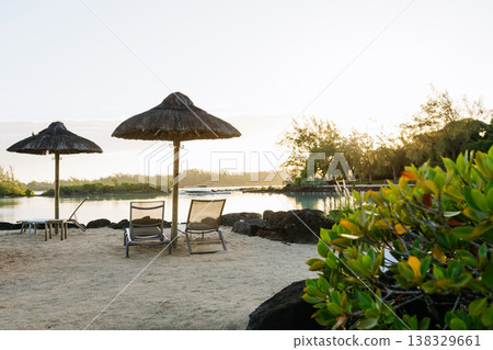 Empty sunbeds and umbrellas on tropical beach in Mauritius resort. Empty sunbeds and umbrellas on tropical beach in Mauritius resort. 138329661