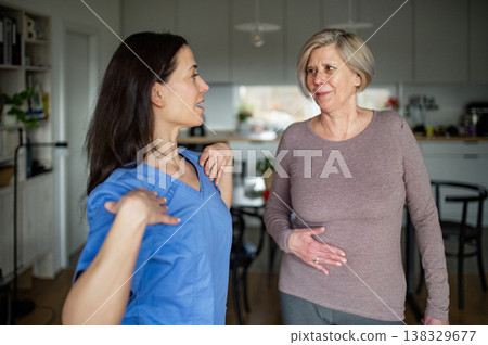 Physiotherapist helping senior woman during rehabilitation exercise at home. 138329677