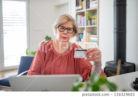 Older woman making online payment, using laptop at home. Older woman making online payment, using laptop at home. 138329683