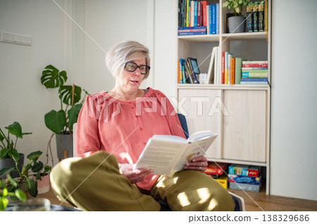 Smiling elderly woman reading book at home. 138329686