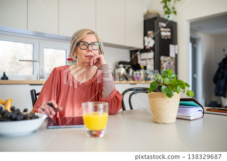 Senior woman working on tablet at home office during retirement. Senior woman working on tablet at home office during retirement. 138329687