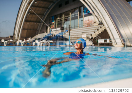 Elderly woman in swimming pool. Older female exercising for vitality and longevity. 138329702