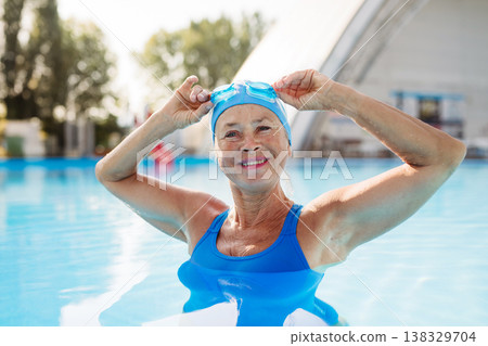 Elderly woman in swimming pool. Older female exercising for vitality and longevity. Elderly woman in swimming pool. Older female exercising for vitality and longevity. 138329704