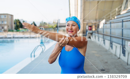 Older female swimmer stretching before swim in pool. Older female swimmer stretching before swim in pool. 138329709
