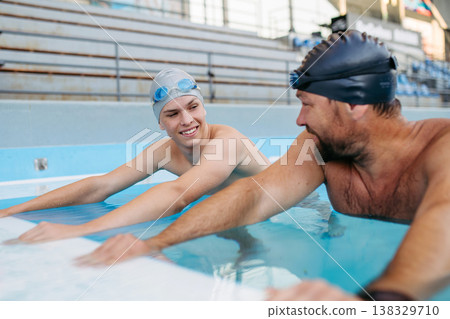 Father and teenage son enjoying swim training together. Father and teenage son enjoying swim training together. 138329710