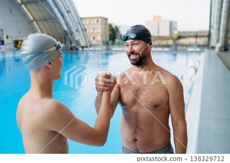 Portrait of coach with teen swimmer, standing by pool. Portrait of coach with teen swimmer, standing by pool. 138329712