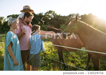 Family watching horses in countryside at sunset. 138329716
