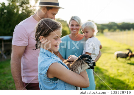 Family petting little goat at farm. 138329719