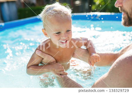 Father playing with little son in pool. Father playing with little son in pool. 138329729