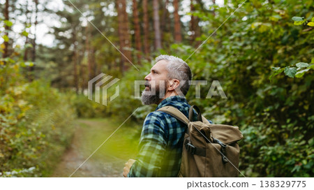 Handsome man standing in the middle of nature, enjoying peaceful atmosphere of the forest, forestbathing. Handsome man standing in the middle of nature, enjoying peaceful atmosphere of the forest, forestbathing. 138329775