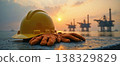Hard hat and gloves near offshore oil rigs sunrise 138329829
