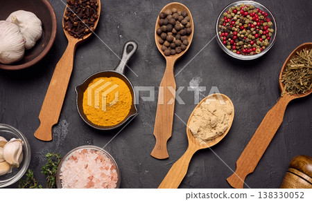 Various ground spices in wooden spoons, olive oil on dark table 138330052