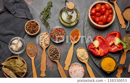 Spices in spoons and bowls on a dark background: turmeric, paprika, anise, cloves, pepper, salt, flax, ginger, cumin. Cooking ingredients, top view. 138330053