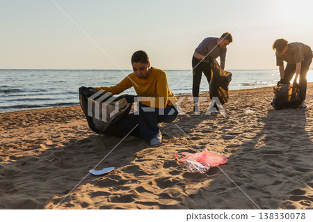 Earth day. Volunteers activists team collects garbage cleaning of beach coastal zone. Woman mans puts plastic trash in garbage bag on ocean shore. Environmental conservation coastal zone cleaning Earth day. Volunteers activists team collects garbage cleaning of beach coastal zone. Woman mans puts plastic trash in garbage bag on ocean shore. Environmental conservation coastal zone cleaning 138330078