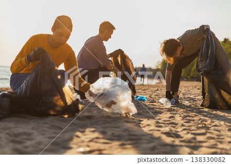 Earth day. Volunteers activists collects garbage cleaning of beach coastal zone. Woman and mans puts plastic trash in garbage bag on ocean shore. Environmental conservation coastal zone cleaning 138330082