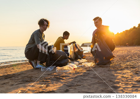 Earth day. Volunteers activists team collects garbage cleaning of beach coastal zone. Woman mans puts plastic trash in garbage bag on ocean shore. Environmental conservation coastal zone cleaning 138330084