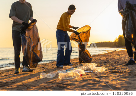 Earth day. Volunteers activists team collects garbage cleaning of beach coastal zone. Woman mans with trash in garbage bag on ocean shore. Environmental conservation coastal zone cleaning Earth day. Volunteers activists team collects garbage cleaning of beach coastal zone. Woman mans with trash in garbage bag on ocean shore. Environmental conservation coastal zone cleaning 138330086