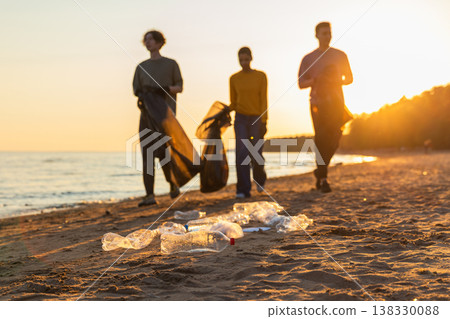 Earth day. Volunteers activists team collects garbage cleaning of beach coastal zone. Woman mans with trash in garbage bag on ocean shore. Environmental conservation coastal zone cleaning Earth day. Volunteers activists team collects garbage cleaning of beach coastal zone. Woman mans with trash in garbage bag on ocean shore. Environmental conservation coastal zone cleaning 138330088