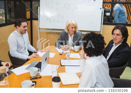 Teamwork brainstorm. Coworkers cooperating working together at office meeting. Colleagues discussing project ideas. Group of people in creative office discussing business. Young professional team Teamwork brainstorm. Coworkers cooperating working together at office meeting. Colleagues discussing project ideas. Group of people in creative office discussing business. Young professional team 138330106