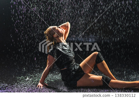 Contemporary woman dancer posing in rain water on black background. Female artist performer dancing with expression. Modern ballerina dancing in darkness. Passion dance in dark. Flexibility balance 138330112