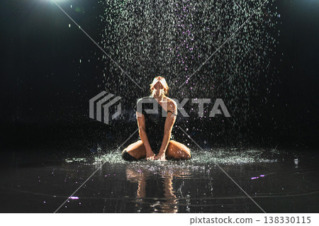 Contemporary woman dancer posing in rain water on black background. Female artist performer dancing with expression. Modern ballerina dancing in darkness. Passion dance in dark. Flexibility balance 138330115