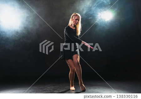Contemporary woman dancer posing on black background with smoke. Adult female artist performer dancing with expression. Modern ballerina dancing in darkness. Passion dance in dark. Flexibility balance Contemporary woman dancer posing on black background with smoke. Adult female artist performer dancing with expression. Modern ballerina dancing in darkness. Passion dance in dark. Flexibility balance 138330116