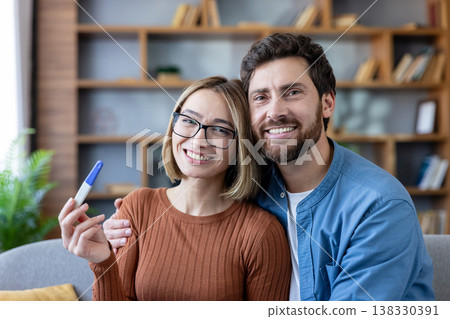 Young smiling couple embracing on a sofa, sharing happiness and excitement after receiving a positive pregnancy test result, looking forward to starting their family Young smiling couple embracing on a sofa, sharing happiness and excitement after receiving a positive pregnancy test result, looking forward to starting their family 138330391