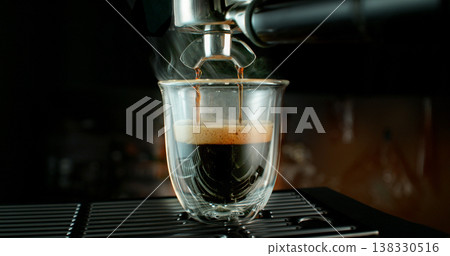 Fresh espresso pouring from coffee machine into glass cup with rich crema and rising steam. Warm cinematic scene capturing preparation of black coffee in cozy atmosphere. Fresh espresso pouring from coffee machine into glass cup with rich crema and rising steam. Warm cinematic scene capturing preparation of black coffee in cozy atmosphere. 138330516