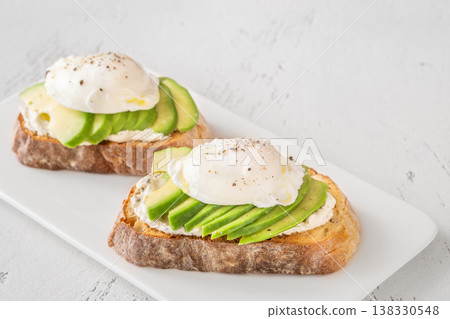 Avocado toast with poached eggs on artisan bread plate Avocado toast with poached eggs on artisan bread plate 138330548